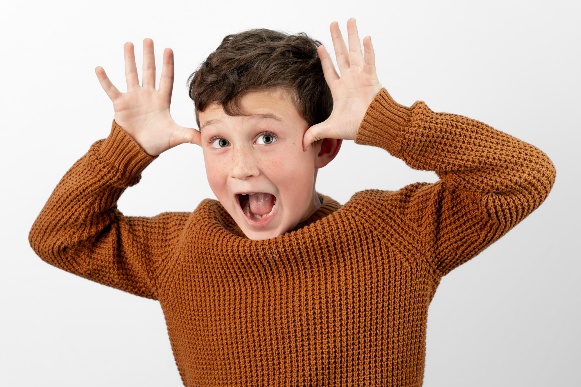 a smiling boy makes antlers out of his hands