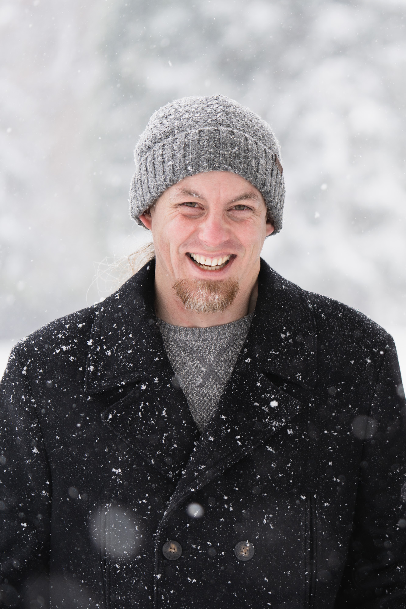 a man in a black jacket smiling in the snow