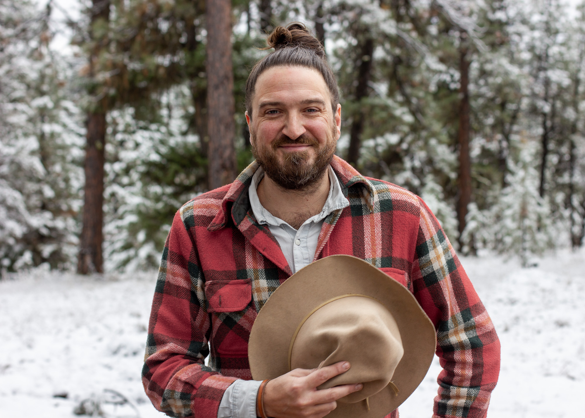 A smiling man standing in a snowy forest