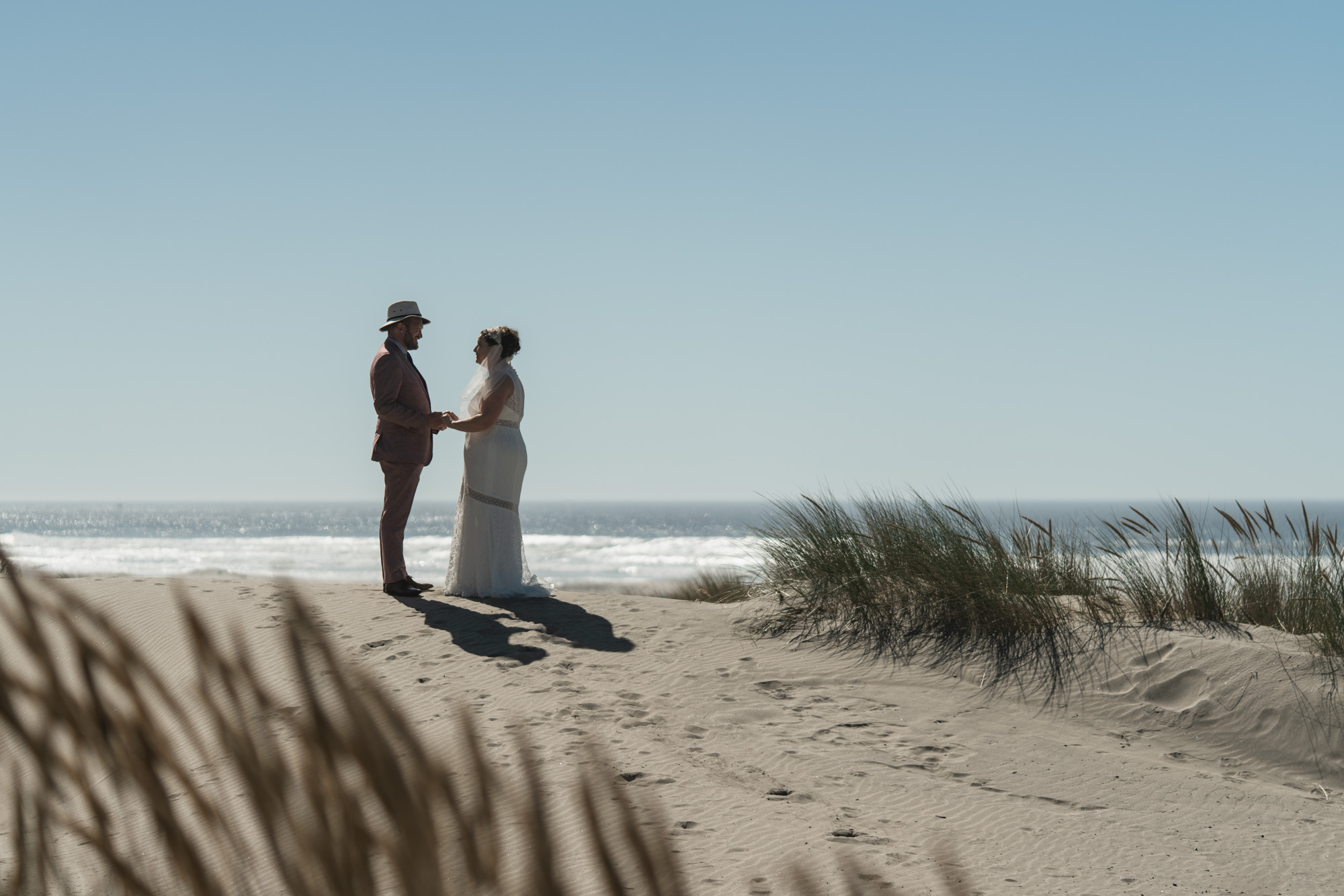 a bride and groom on a sand dune