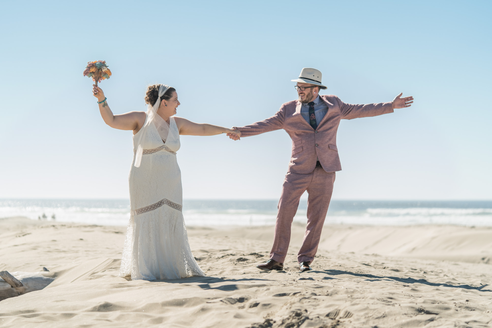 a bride and groom dancing in the sand