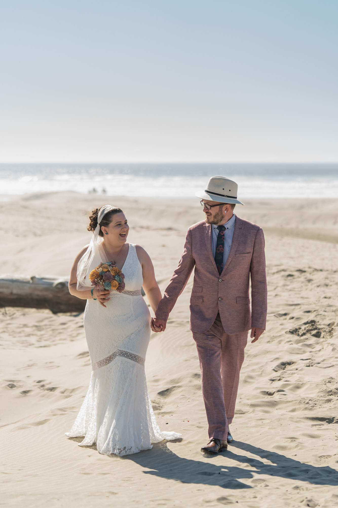 a newly married couple walking in the sand